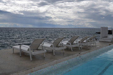 Fototapeta premium sea ​​view before the rain with white sunbeds for sunbathing