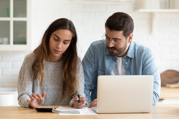 Concentrated young married spouse calculating monthly family budget together.