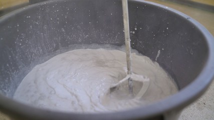 The primer is mixed in a large bucket using a construction mixer. The mixer in the bucket mixes the mixture