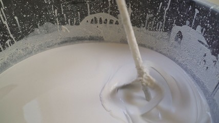 The primer is mixed in a large bucket using a construction mixer. The mixer in the bucket mixes the mixture