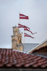 4 Latvia latvian flags waving on 4 flagpoles in wind. Clear blue sky in warm winter day.