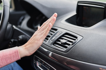 Woman hand on air conditioner ventilation grille in the car. Climate control panel