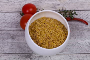 Raw bulgur in the bowl with tomatoes and garlic