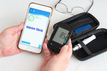 Measuring glucose levels and using smart phone. Healthcare and medical concept - obrazy, fototapety, plakaty