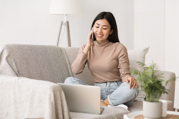 Multitasking concept. Girl using laptop and talking on cellphone