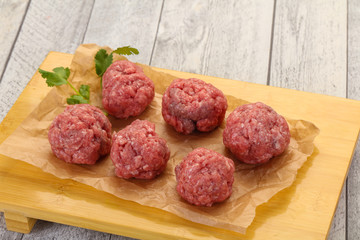 Raw meatball over wooden background