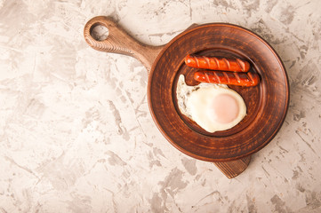 Close-up of sausages and fried eggs. Sausages on a plate and place for text. Breakfast fried eggs and bavarian sausages on a clay plate and copy space.