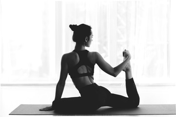 Fit woman making mermaid asana exercise, back view