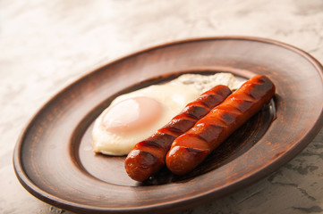Close-up of sausages and fried eggs. Sausages on a plate and place for text. Breakfast fried eggs and bavarian sausages on a clay plate and copy space.