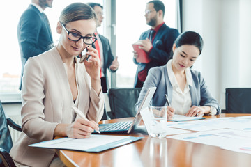 Business woman working while the men are chatting idly