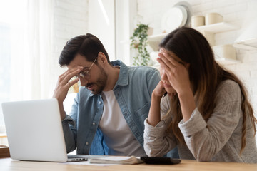 Young family couple feeling disappointed by high utility bills.