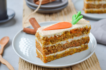 Carrot Cake Day.  National holiday. Carrot cake with cream cheese frosting decorated with chocolate carrots on an orange background, stylized table setting.  Close-up, top view