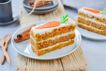 Carrot Cake Day.  National holiday. Carrot cake with cream cheese frosting decorated with chocolate carrots on a light wooden background. Close-up, top view .