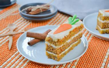 Carrot Cake Day.  National holiday. Carrot cake with cream cheese frosting decorated with chocolate carrots on an orange background, stylized table setting.  Close-up, top view .