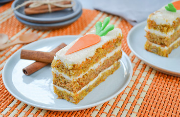 Carrot Cake Day.  National holiday. Carrot cake with cream cheese frosting decorated with chocolate carrots on an orange background, stylized table setting.  Close-up, top view .