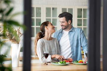 Happy mixed race girl chatting with boyfriend, preparing romantic dinner.