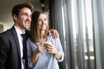 Beautiful young couple talking to each other and smiling while enjoying coffee