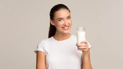 Millennial Girl Holding Glass Of Milk Standing On Gray Background