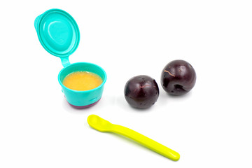 Fototapeta premium Baby first solids. Weaning. Homemade vegetable plum puree, raw plums and a spoon