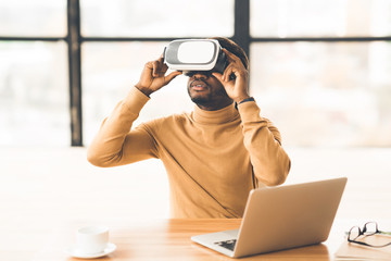 Afro businessman wearing augmented reality goggles at home