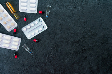  Ampoules for injections, pills and capsules on a black background. Copy space.