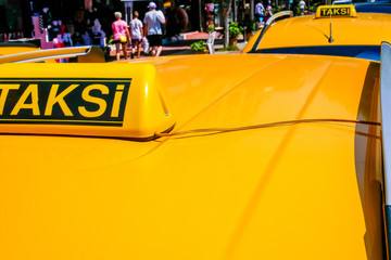 Taxi sign on yellow roof of the car