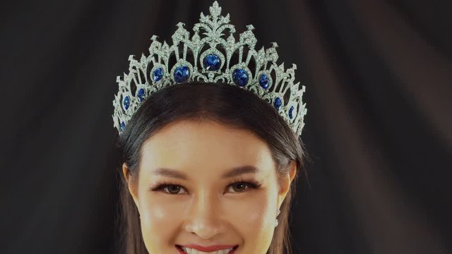 Stunning Asian beauty queen with long artificial eyelashes and perfect skin smiles and poses -close up