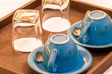Close-up view of the blue coffee mug, clear glass for drinking water, placed on a tray to bring clear drinks, seen at resorts, hotels or bakeries