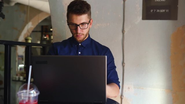 Young freelancer man opens and starts using laptop with biometric face recognition system in office. Developer begins his remote working day in cafe. Computer with facial identification.
