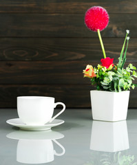 Coffee cup and Artificial flower vase bouquet over table