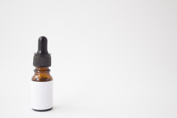 Dropper glass Bottle Mock-Up. Oily drop falls from cosmetic pipette on white background