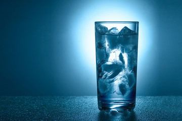 glass of pure mineral water with ice on a blue background