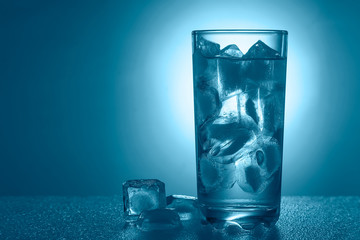 glass of pure mineral water with ice on a blue background