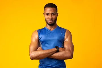 Tuinposter Afro sportsman with folded arms at studio © Prostock-studio