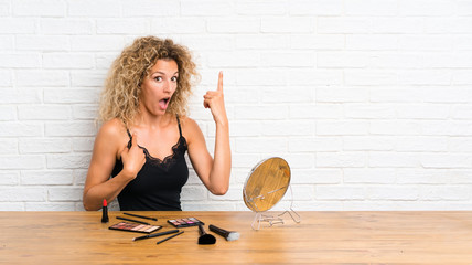 Young woman with lots of makeup brush in a table with surprise facial expression
