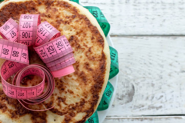 a stack of pancakes on a plate with a centimeter tape on top on a wooden table. the concept of an...