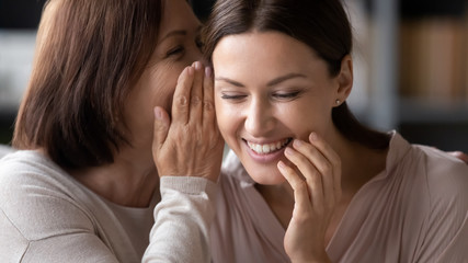 Smiling senior mom and adult daughter share secrets