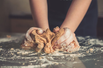 girl preparing cookies in the shape of a heart for the holiday Valentine's Day at home, in a small...
