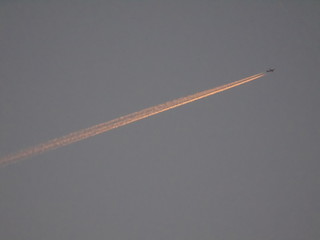 Areo con scia rosata nel cielo al tramonto