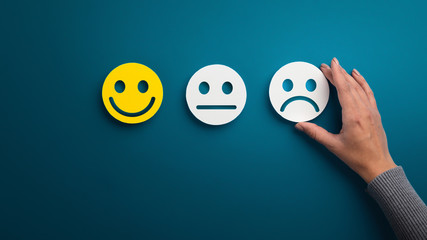 Woman choosing sad or bad smiley face emotion