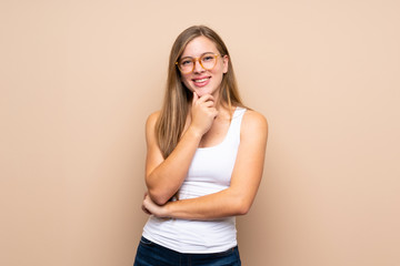 Teenager blonde girl over isolated background with glasses and smiling