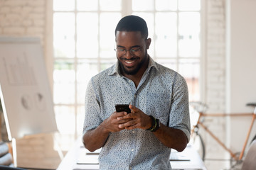 Smiling biracial male employee using cellphone in office boardroom