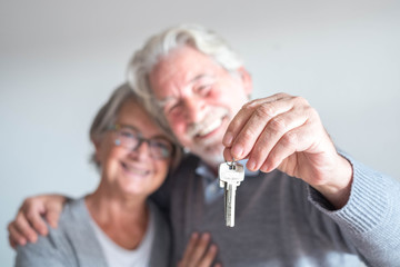 couple of two seniors after buy a new house or car and go to live together - man holding a key and mature man and woman looking at it - obrazy, fototapety, plakaty