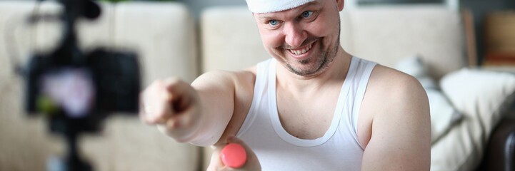 Happy Blogger with Dumbbell Training in Apartment. Smiling Sportsman Recording Video on Digital...