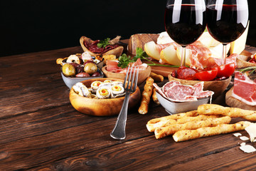 Italian antipasti wine snacks set. Cheese variety, Mediterranean olives, seafood salad, Prosciutto di Parma, tomatoes, anchovy and wine in glasses
