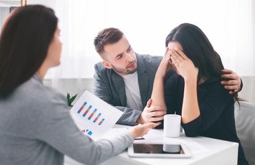 Saleswoman document with bad news to worried couple