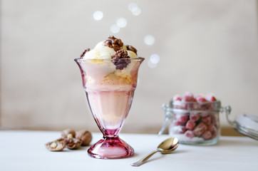 Creamy ice cream with honey and walnuts. Served in a bowl with ice cream, garnished with walnuts and honey. On the table is a jar with dried strawberries, a spoon and a walnut.