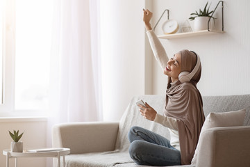 Jouful Muslim Girl In Wireless Headphones Listening Music Online On Smartphone