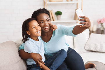 Happy black mom and daughter taking selfie - obrazy, fototapety, plakaty