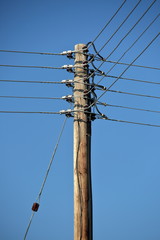 electric pole and wires against blue clear sky, close up